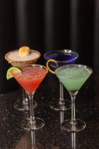 four colorful martinis on a table 